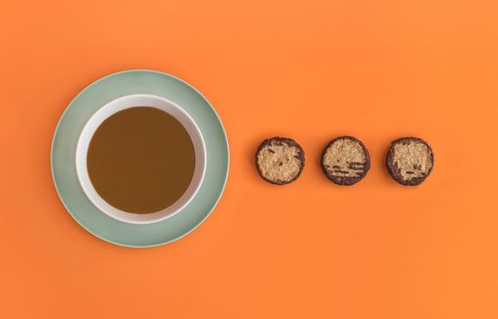 Chocolate bowl on a green light plate and three cookies. Orange background. Copy space,