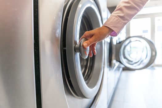 inserting dirty clothes into the washing machine in the laundry room.