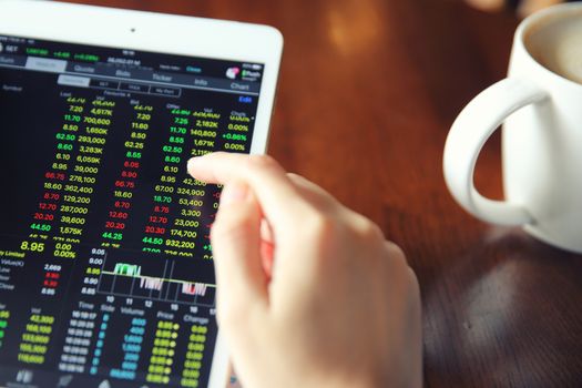 Woman hand Trading online on tablet with business paper and coffee