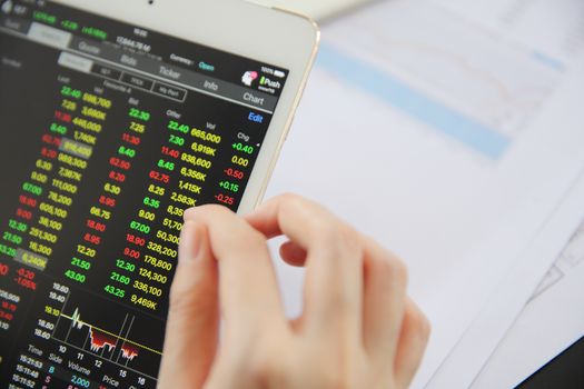 Woman hand Trading online on tablet with business paper and coffee