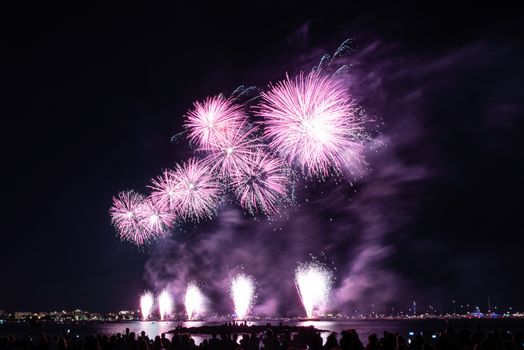 Scenic fireworks glowing in the night for the 14th of July celebrations in the harbor of Cannes, Cote d'Azur, France