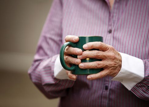 Hands of elderly woman with arthritis holding cup