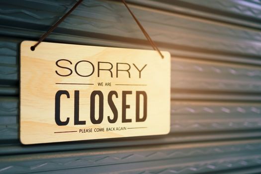 A Sign board of sorry we are closed hang on door of business shop with nature green background