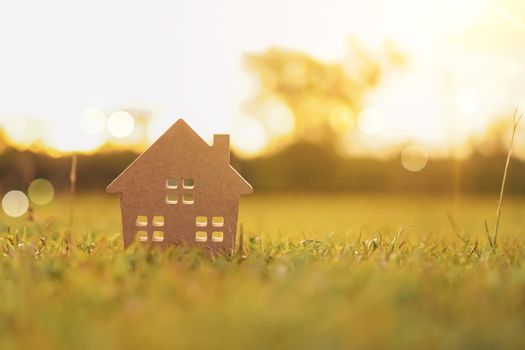 Closed up tiny home model on green grass with sunlight background.