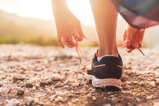 Woman wear running shoe on to walking and running on nature green background.Health exercise concept.