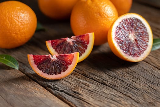 Sliced Sicilian Blood oranges fruits over old dark wooden background. Top view.