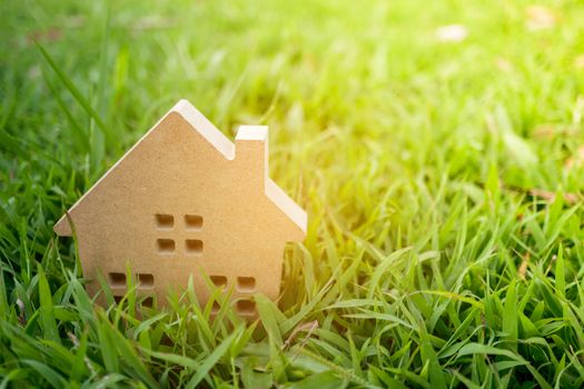 Closed up tiny home model on green grass with sunlight background.