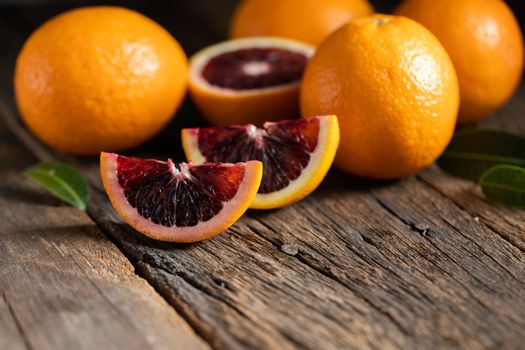 Sliced Sicilian Blood oranges fruits over old dark wooden background. Top view.