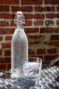 Bottle of cold water in hot summer day on brick wall background