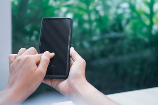 Woman hand use smartphone to do work business, social network, communication in public cafe work space area.