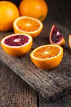 Sliced Sicilian Blood oranges fruits over old dark wooden background. Top view.