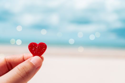 Hand hold little heart meaning feel love with summer beach with blue sky background.