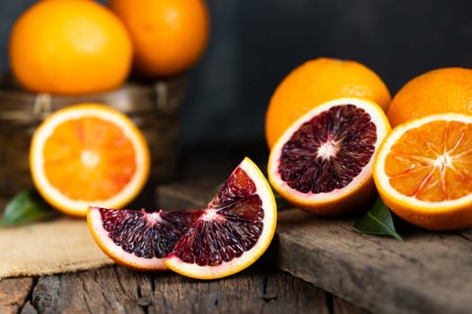 Sliced Sicilian Blood oranges fruits over old dark wooden background. Top view.