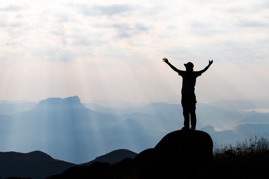 Silhouette of man hold up hands on the peak of mountain,success concept