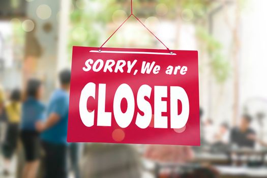 A Sign board of sorry we are closed hang on door of business shop with nature green background