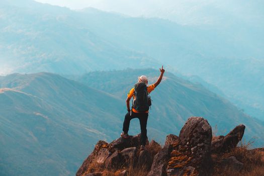 Silhouette of man hold up hands on the peak of mountain,success concept