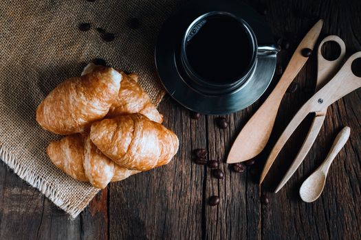 Coffee and croissants on the wooden background, top view