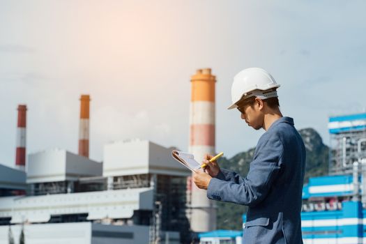 Engineer with a coal power plant in the background, Thailand