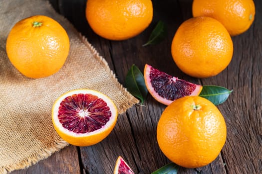 Sliced Sicilian Blood oranges fruits over old dark wooden background. Top view.