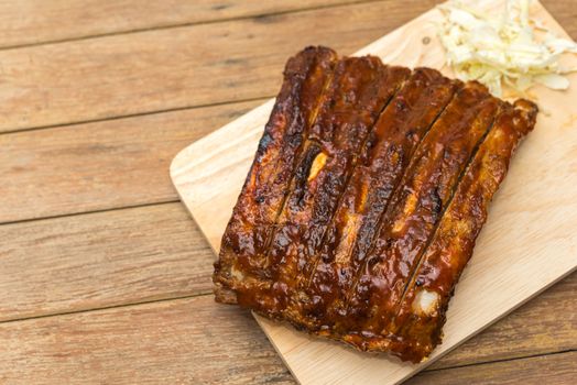 Roasted Pork Spare Ribs Barbecue or Pork Ribs with BBQ Sauce on wooden cutting board in kitchen at Thai street food market or restaurant