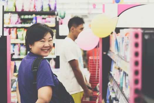 Asian woman with many types of cosmetics for beauty and skin health products for sale in supermarket open daily