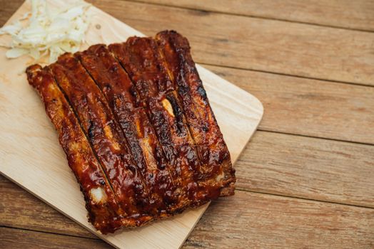 Roasted Pork Spare Ribs Barbecue or Pork Ribs with BBQ Sauce on wooden cutting board in kitchen at Thai street food market or restaurant