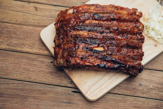 Roasted Pork Spare Ribs Barbecue or Pork Ribs with BBQ Sauce on wooden cutting board in kitchen at Thai street food market or restaurant