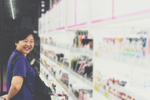 Asian woman with many types of cosmetics for beauty and skin health products for sale in supermarket open daily