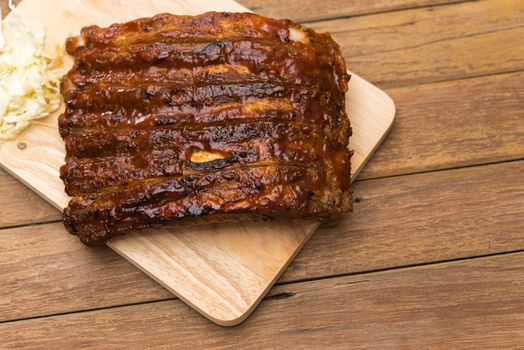 Roasted Pork Spare Ribs Barbecue or Pork Ribs with BBQ Sauce on wooden cutting board in kitchen at Thai street food market or restaurant