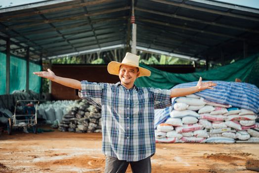 Asian man farmer agriculturist happy at a Fertilizer composting plant with Organic Fertilizer, Compost (Aerobic Microorganisms) from animal waste for use in the organic agriculture industry