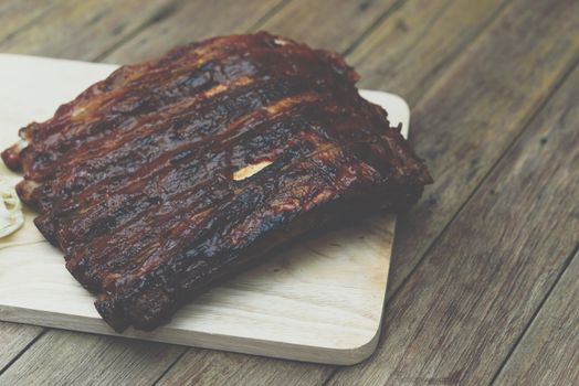 Roasted Pork Spare Ribs Barbecue or Pork Ribs with BBQ Sauce on wooden cutting board in kitchen at Thai street food market or restaurant