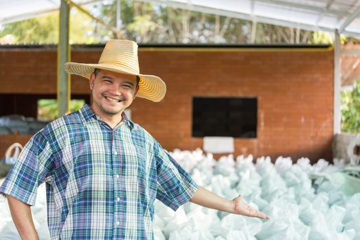 Asian man farmer agriculturist happy at a Fertilizer composting plant with Organic Fertilizer, Compost (Aerobic Microorganisms) from animal waste for use in the organic agriculture industry