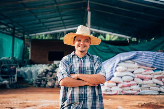 Asian man farmer agriculturist happy at a Fertilizer composting plant with Organic Fertilizer, Compost (Aerobic Microorganisms) from animal waste for use in the organic agriculture industry