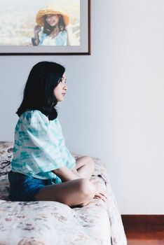 Asian pretty woman short jeans sitting on bed in bedroom alone with loneliness and lonely emotion in concept depressed feeling, depression, problem in life