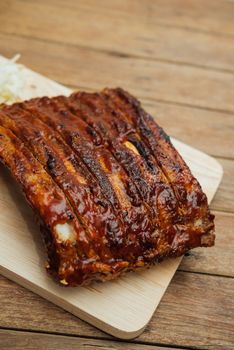 Roasted Pork Spare Ribs Barbecue or Pork Ribs with BBQ Sauce on wooden cutting board in kitchen at Thai street food market or restaurant