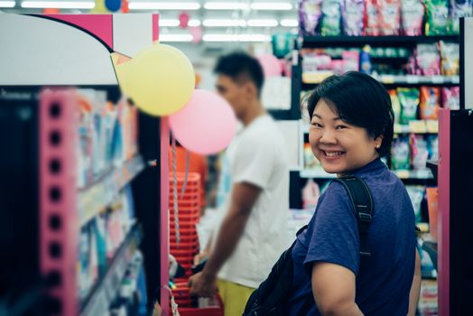 Asian woman with many types of cosmetics for beauty and skin health products for sale in supermarket open daily