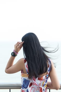 Asian pretty woman with hair blown relax at sea viewpoint with loneliness and lonely emotion in concept travel, vacation, leisure in life