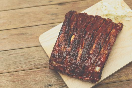 Roasted Pork Spare Ribs Barbecue or Pork Ribs with BBQ Sauce on wooden cutting board in kitchen at Thai street food market or restaurant