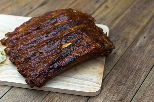 Roasted Pork Spare Ribs Barbecue or Pork Ribs with BBQ Sauce on wooden cutting board in kitchen at Thai street food market or restaurant