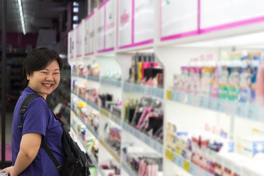 Asian woman with many types of cosmetics for beauty and skin health products for sale in supermarket open daily