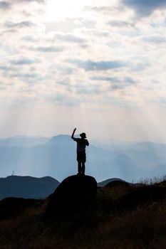 Silhouette of man hold up hands on the peak of mountain,success concept