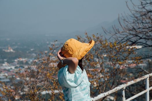 Asian pretty cute woman with hat relax at seaside city landscape viewpoint on mountain with happy and freedom emotion in concept travel, vacation, leisure in life