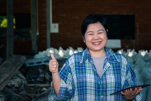 Asian woman smart farmer agriculturist happy at a Fertilizer composting plant with Organic Fertilizer, Compost (Aerobic Microorganisms) from animal waste for use in the organic agriculture industry