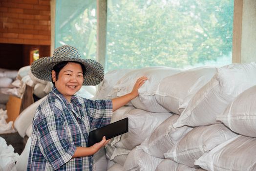 Asian woman smart farmer agriculturist happy at a Fertilizer composting plant with Organic Fertilizer, Compost (Aerobic Microorganisms) from animal waste for use in the organic agriculture industry