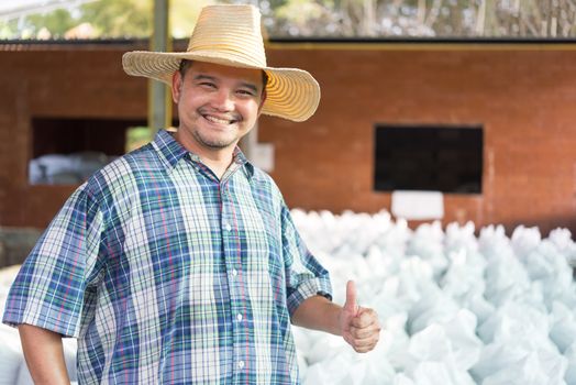 Asian man farmer agriculturist happy thumbs up at a Fertilizer composting plant with Organic Fertilizer, Compost (Aerobic Microorganisms) from animal waste for use in the organic agriculture industry