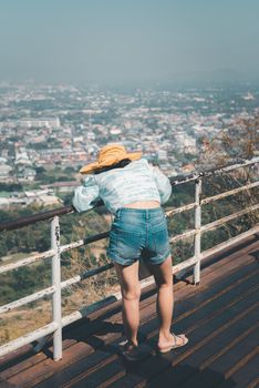 Asian pretty cute woman with hat relax and use smartphone at seaside city landscape viewpoint on mountain with happy and freedom emotion in concept travel, vacation, leisure in life