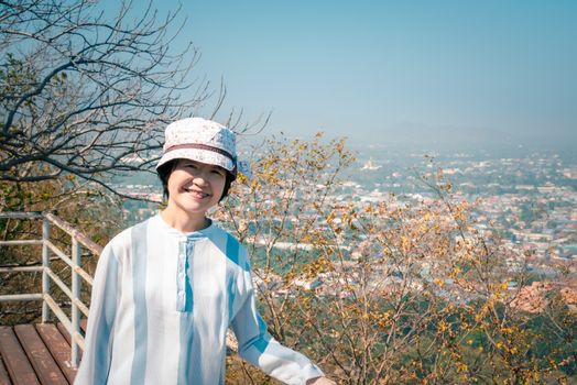 Asian pretty cute woman with hat relax at seaside city landscape viewpoint on mountain with happy and freedom emotion in concept travel, vacation, leisure in life