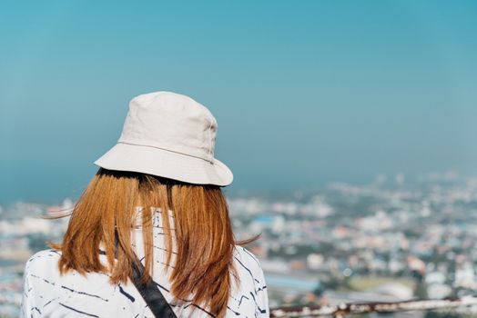 Asian pretty cute woman with hat relax at seaside city landscape viewpoint on mountain with happy and freedom emotion in concept travel, vacation, leisure in life