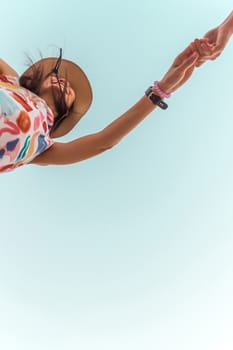 Low angle view of cute three asian women hold hands circle running round camera shot below with sky overhead in concept travel, happy and fun lifestyle, friendship. Pastel vintage style