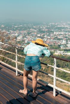 Asian pretty cute woman with hat relax and use smartphone at seaside city landscape viewpoint on mountain with happy and freedom emotion in concept travel, vacation, leisure in life